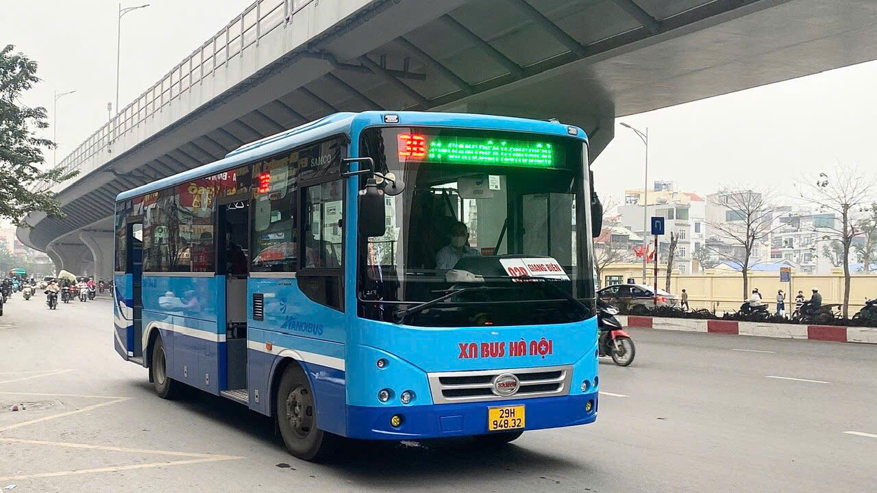 Blue Hanoi city bus operating beneath an urban overpass.